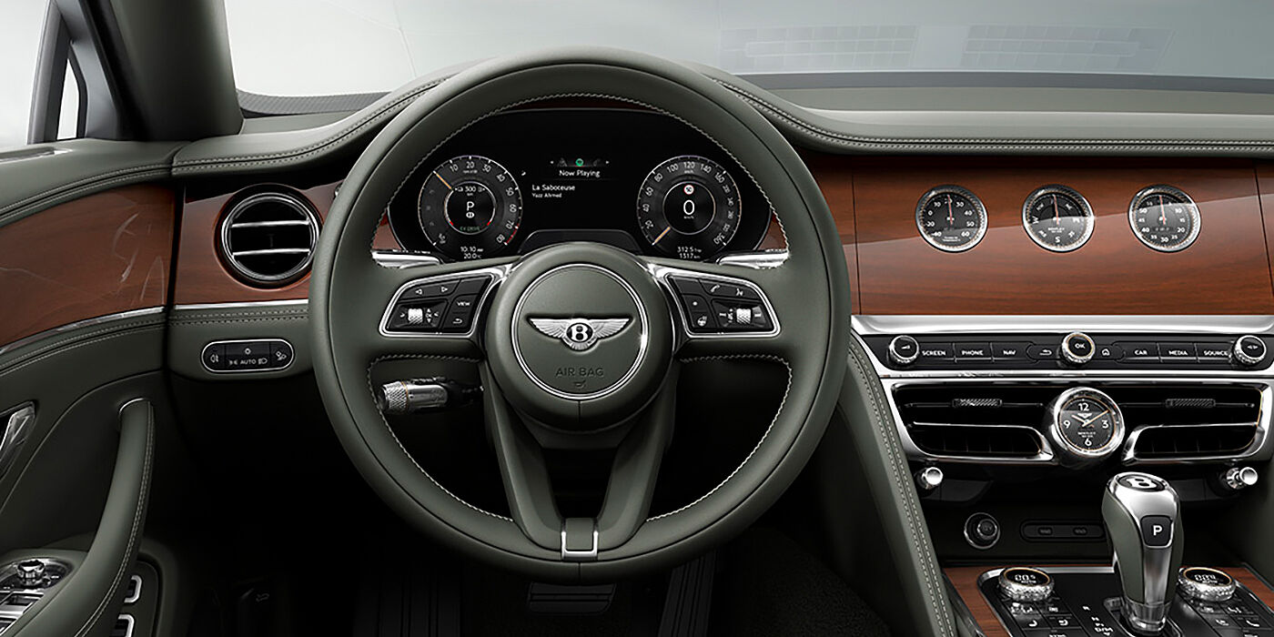 Bentley Hyderabad New Bentley Flying Spur sedan front cabin in Cumbrian Green hide and Crown Cut walnut veneer showing steering wheel and Rotating Display with three clocks on face